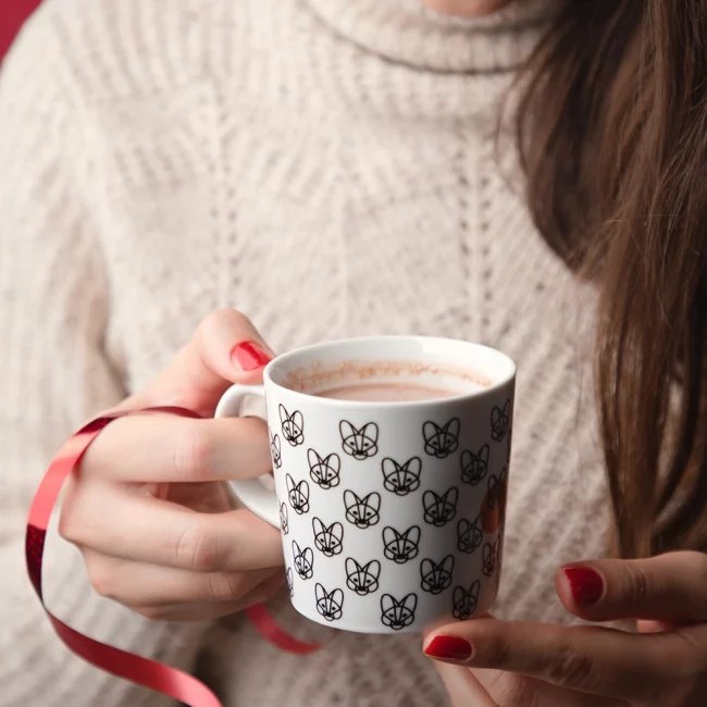 Aguara šolja sa toplom čokoladom u njoj koju drži ženska osoba.